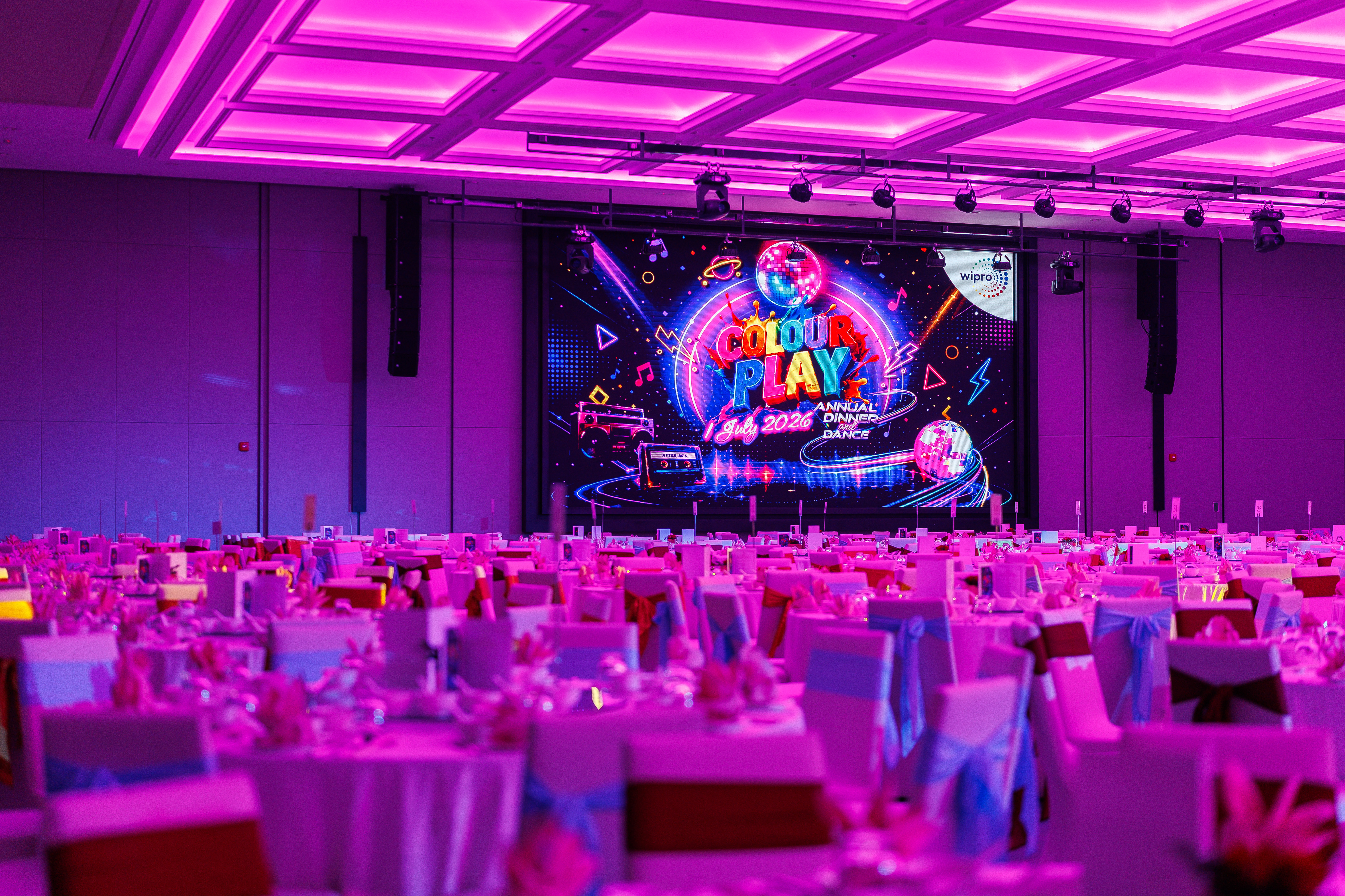 Company gala dinner ballroom setup with stage, LED screen, lighting and banquet tables.